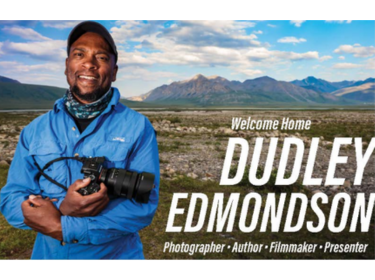 man standing in wilderness holding camera